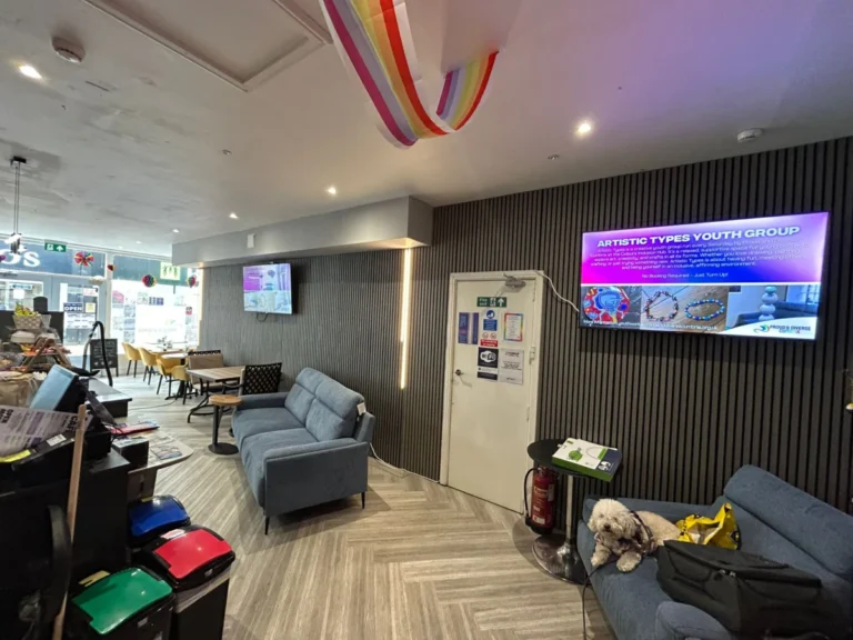 The hub lounge with sofas, a rainbow ceiling decoration and a wall screen