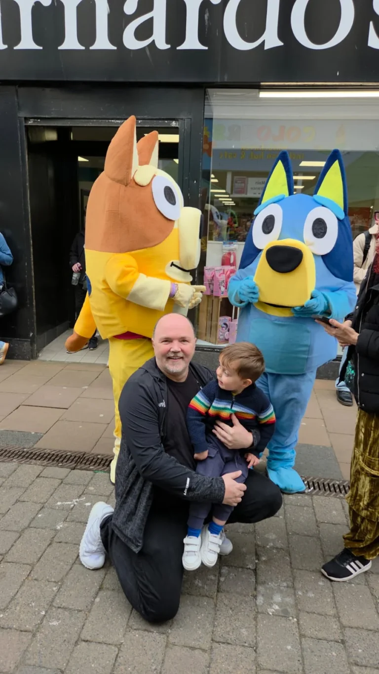 Bingo and Bluey costume characters with a man and a toddler on the high street